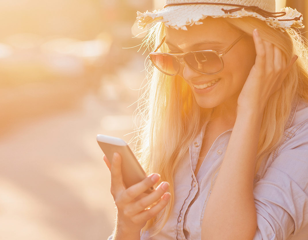 Woman outside smiling at mobile device